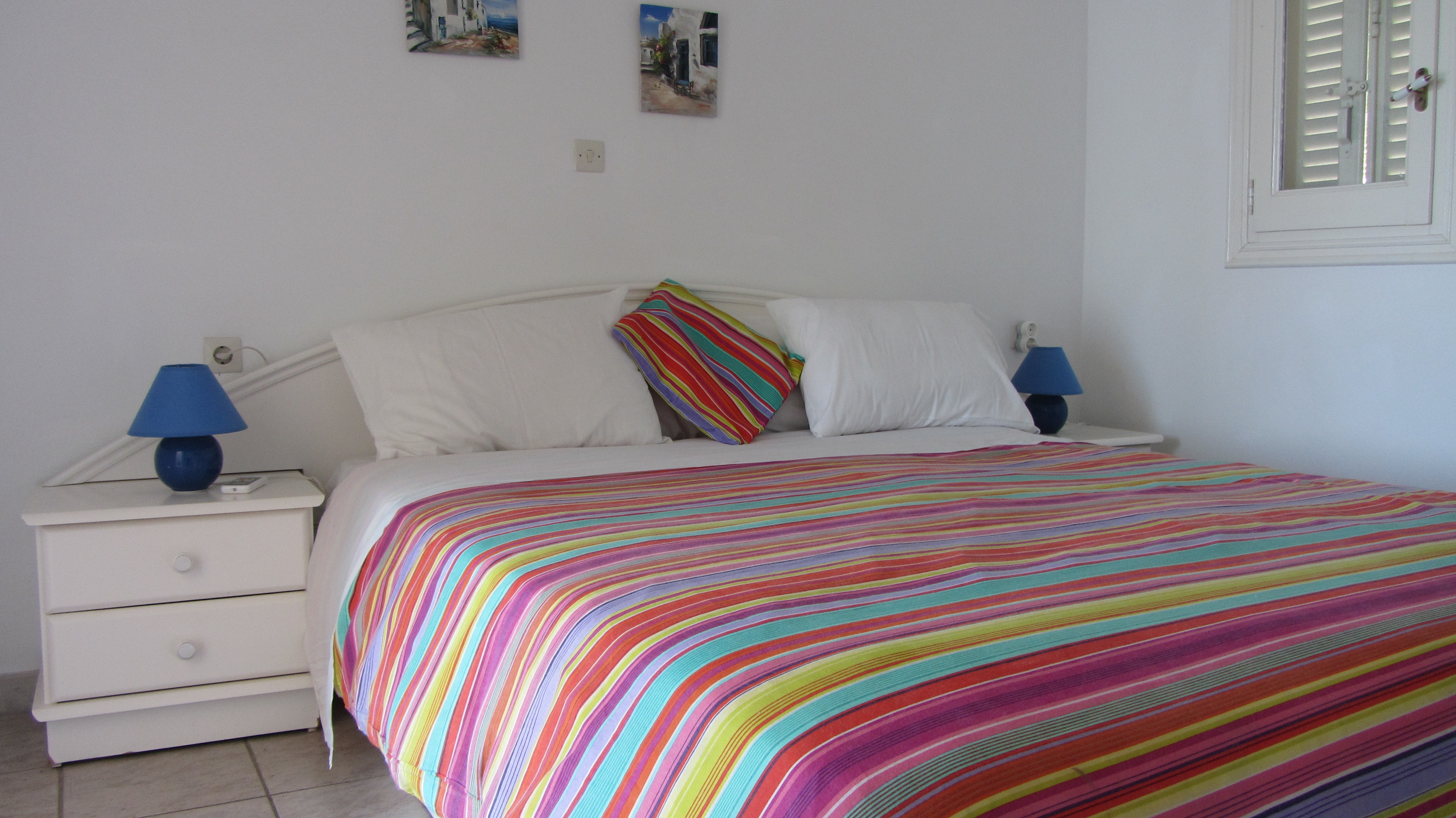 Schlafzimmer mit Doppelbett und bunter Bettwäsche